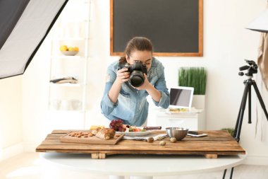 Genç kadın ile profesyonel fotoğraf makinesi fotoğraf stüdyosunda natürmort resim çekme