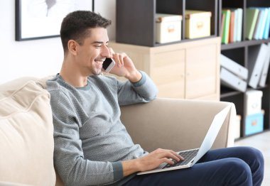 Genç adam evde laptop ile çalışırken Evet