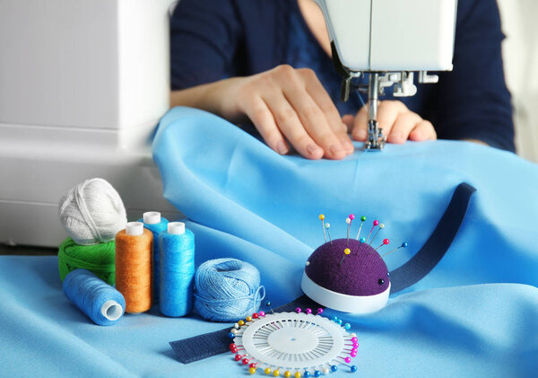 Close up of woman sewing on machine with blue fabric and colorful threads