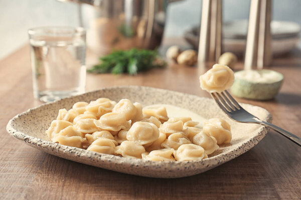 Тарелка с вкусными пельменями на столе
