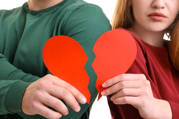 Junges Paar mit gebrochenem Herzen auf weißem Hintergrund. Beziehungsprobleme — Stockfoto