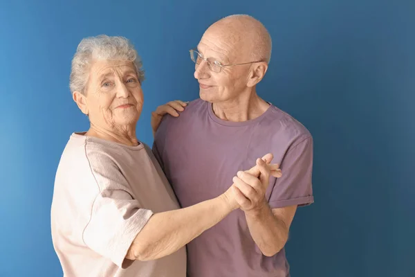 Bonito casal de idosos dançando contra fundo de cor — Fotografia de Stock