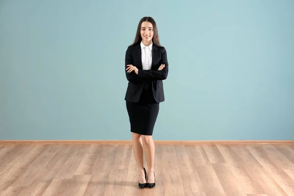 Beautiful young woman in elegant suit against color wall — Stock Photo, Image