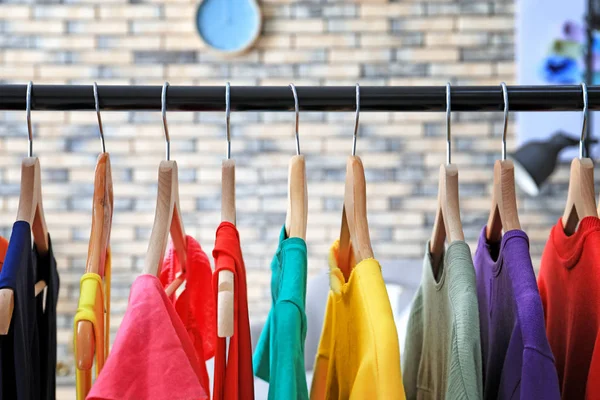 Rack with rainbow clothes on hangers indoors
