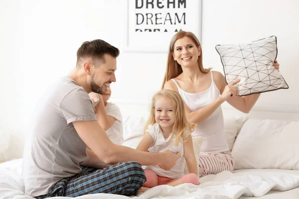 Happy family having pillow fight in bed at home