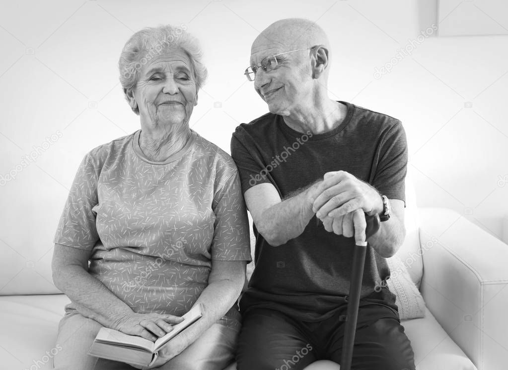 Senior people sitting on couch at home, black and white effect. Elderly care