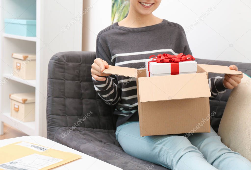 Woman taking gift box out of parcel at home