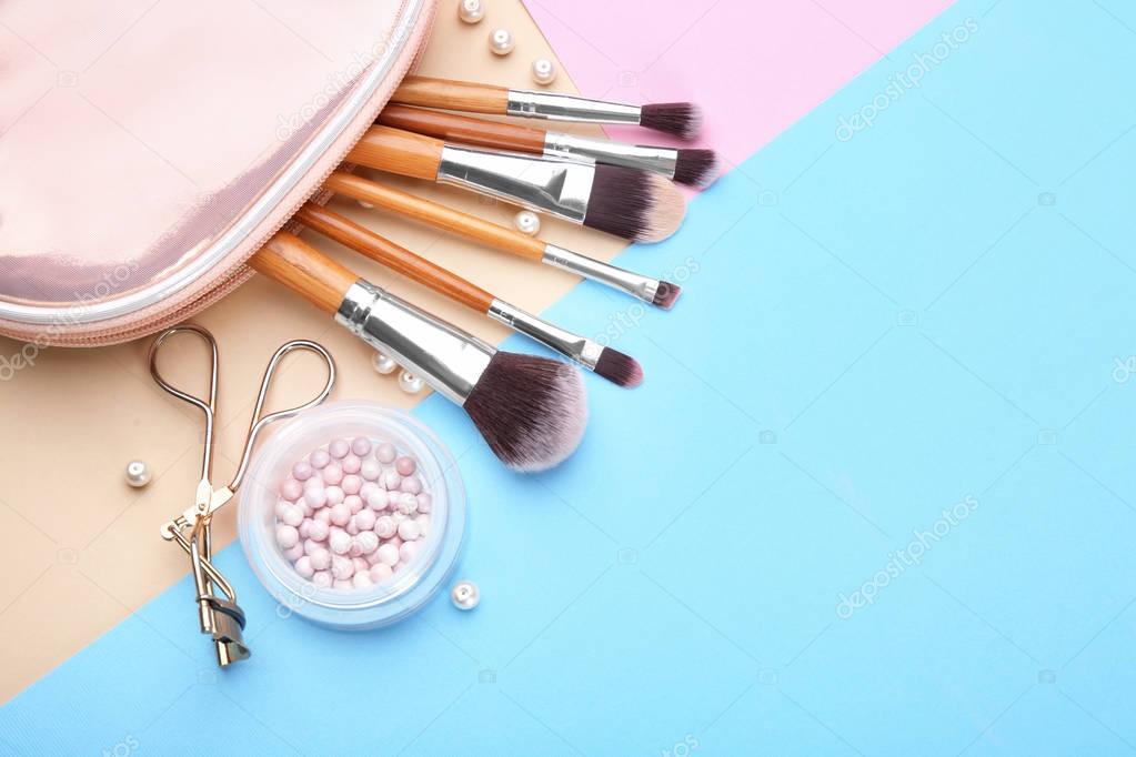 Decorative cosmetics and tools of professional makeup artist on color background