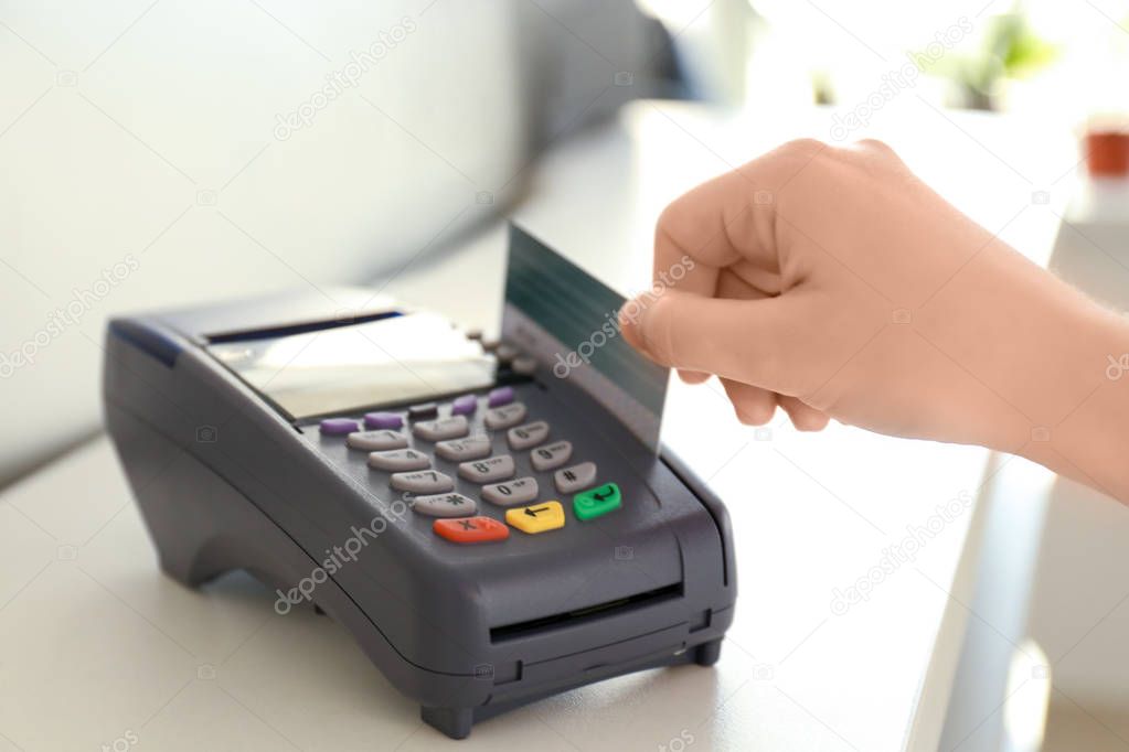 Woman using bank terminal for credit card payment on table