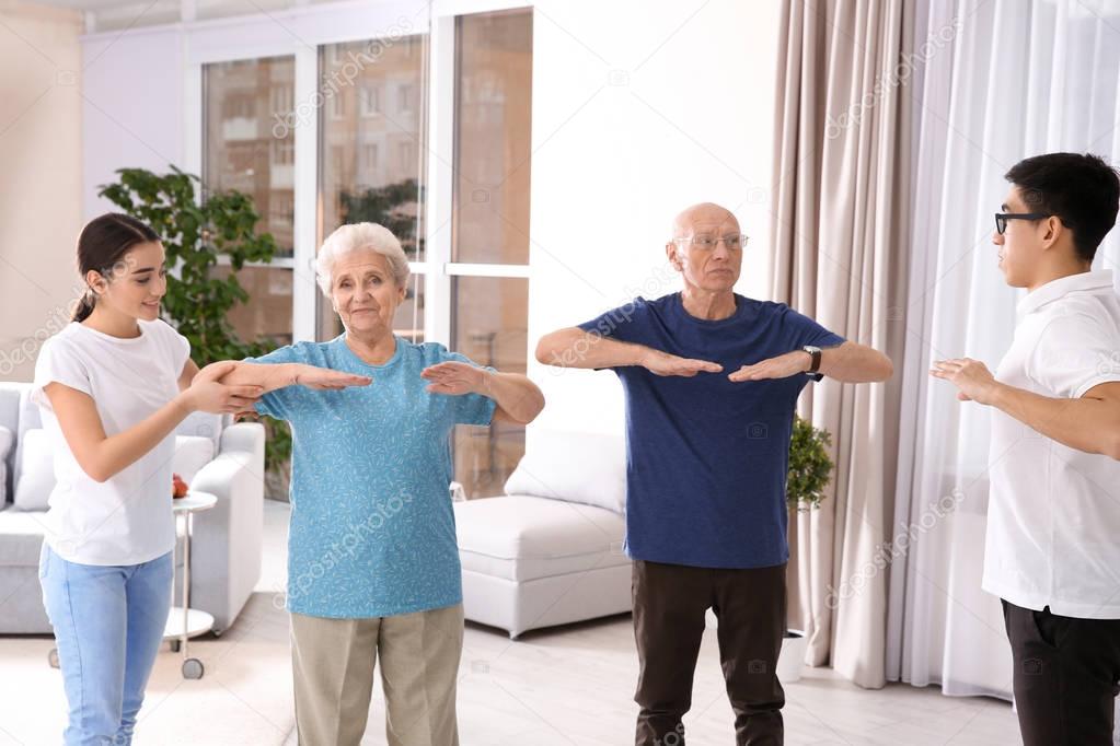 Senior people doing exercises with caregivers at home