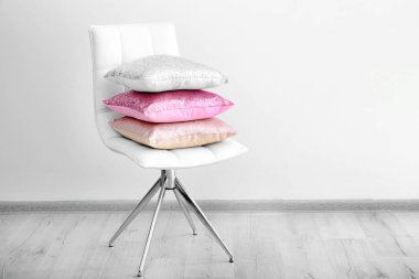 Yastıklar üzerinde beyaz duvar yakın sandalyede yığını