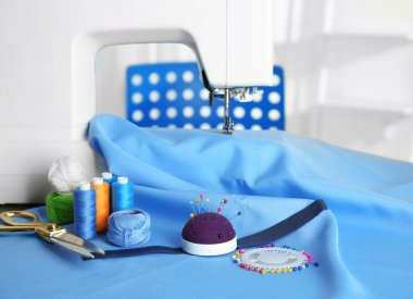 Close up of sewing machine with blue fabric and colorful threads clipart