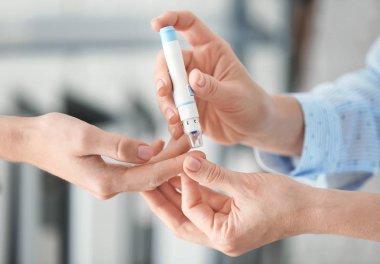 Doktor alarak mazgal ve kalemi, closeup diyabetik hastanın kan örneğini