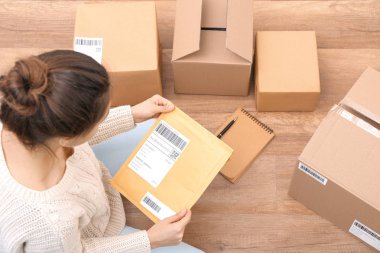 Female startupper preparing parcels for shipment to customers indoors clipart