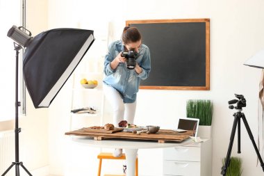 Genç kadın ile profesyonel fotoğraf makinesi fotoğraf stüdyosunda natürmort resim çekme