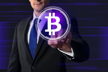 Businessman pushing button with bitcoin sympol on virtual screen against dark background clipart