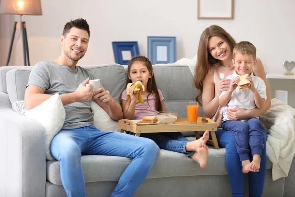 Ontbijten op de sofa thuis en gelukkige familie — Stockfoto
