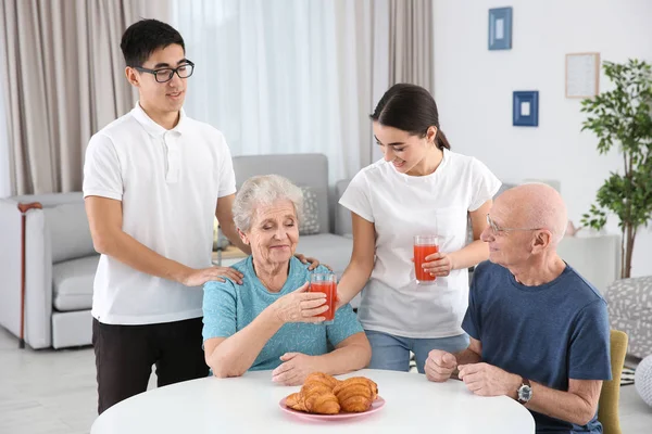 Personas mayores con cuidadores jóvenes en casa —  Fotos de Stock