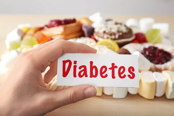 Mulher Segurando Cartão Com Palavra Diabetes Sobre Doces Close — Fotografia de Stock