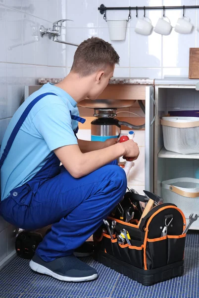 Молодий сантехнік ремонтує раковину на кухні — стокове фото
