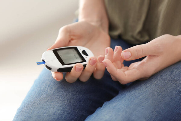 Diabetic woman holding digital glucometer, closeup