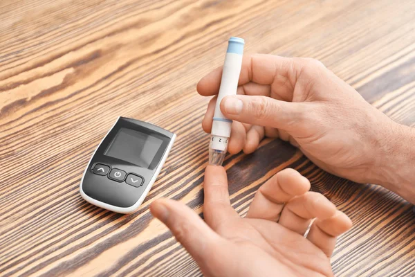 Hombre usando lápiz de lanceta sobre la mesa, primer plano. Monitoreo de diabetes —  Fotos de Stock