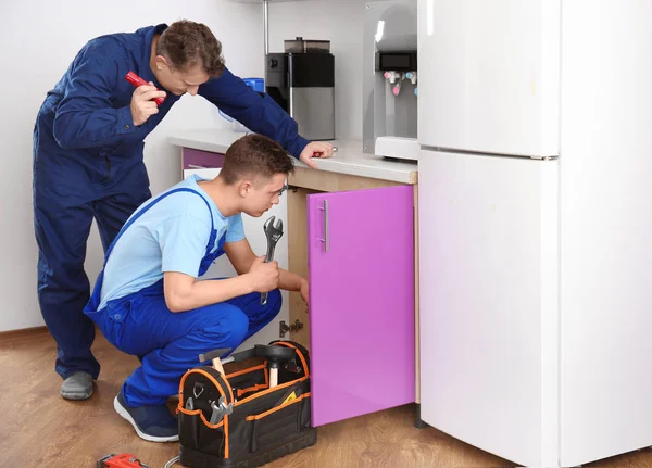 Plombier avec jeune stagiaire en cuisine — Photo