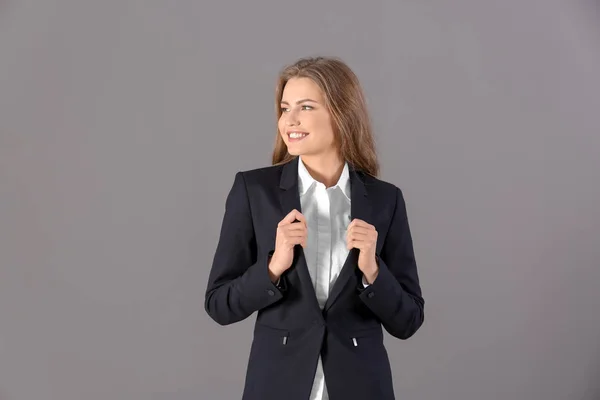 Hermosa mujer de moda en traje elegante sobre fondo gris — Foto de Stock