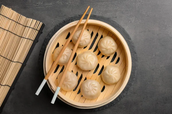 Bamboo steamer with tasty baozi dumplings on table