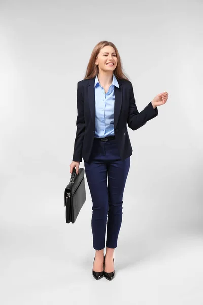 Schöne junge Geschäftsfrau im eleganten Anzug auf hellem Hintergrund — Stockfoto