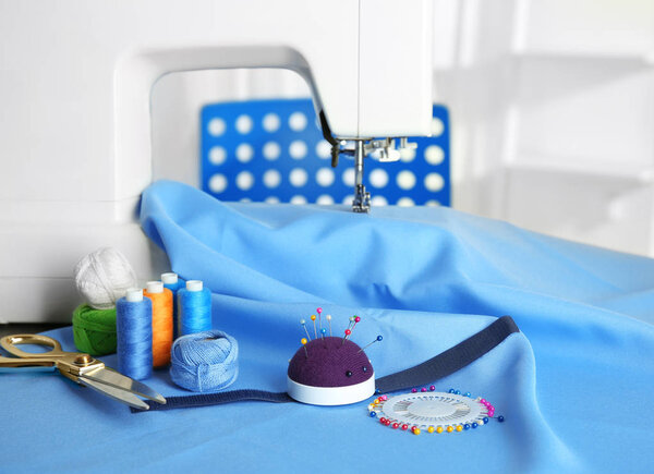 Close up of sewing machine with blue fabric and colorful threads