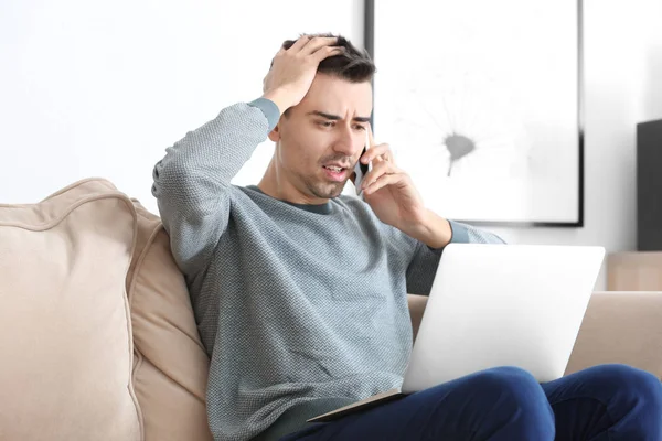Δυσαρεστημένοι Νεαρός Άνδρας Μιλάει Στο Τηλέφωνο Ενώ Εργάζεστε Φορητό Υπολογιστή — Φωτογραφία Αρχείου