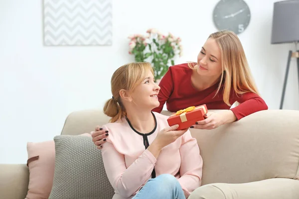 Young woman giving gift box to her mother at home — Stock Photo, Image