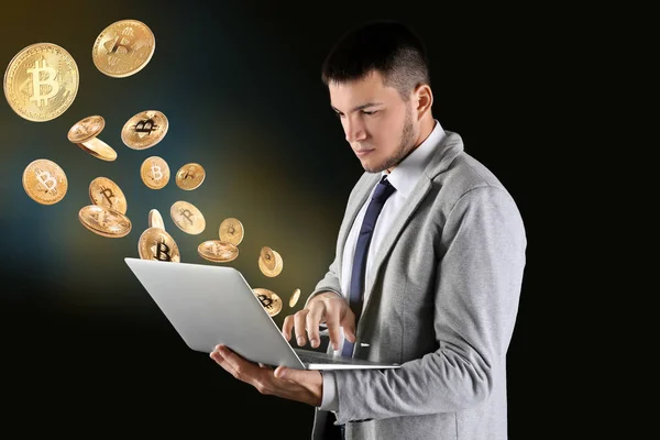 Biznesmen z laptopa i bitcoins na czarnym tle — Zdjęcie stockowe