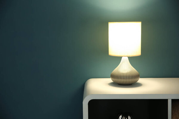 Стол со стильной лампой в модном стиле на темной стене
