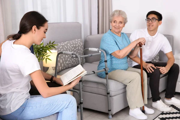 Seniorin mit jungen Pflegekräften zu Hause — Stockfoto
