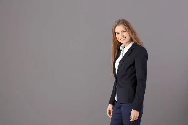 Mooie modieuze vrouw in elegante pak op grijze achtergrond — Stockfoto
