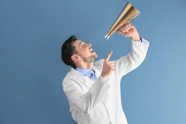 Male doctor with megaphone on blue background