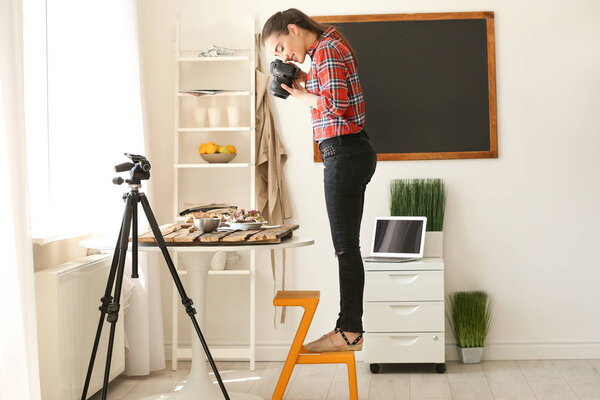 Молодая женщина с профессиональной камерой готовит натюрморт в фотостудии
