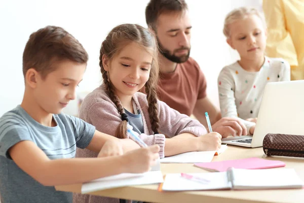 Enfants faisant leurs devoirs avec l'enseignant en classe à l'école — Photo