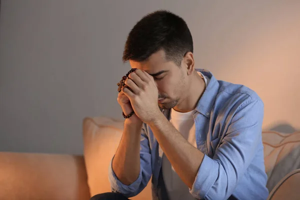 Religiöser Junger Mann Mit Rosenkranzperlen Der Hause Betet — Stockfoto