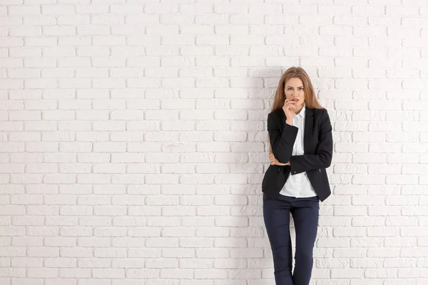 Schöne modische Frau im eleganten Anzug gegen weiße Backsteinmauer — Stockfoto