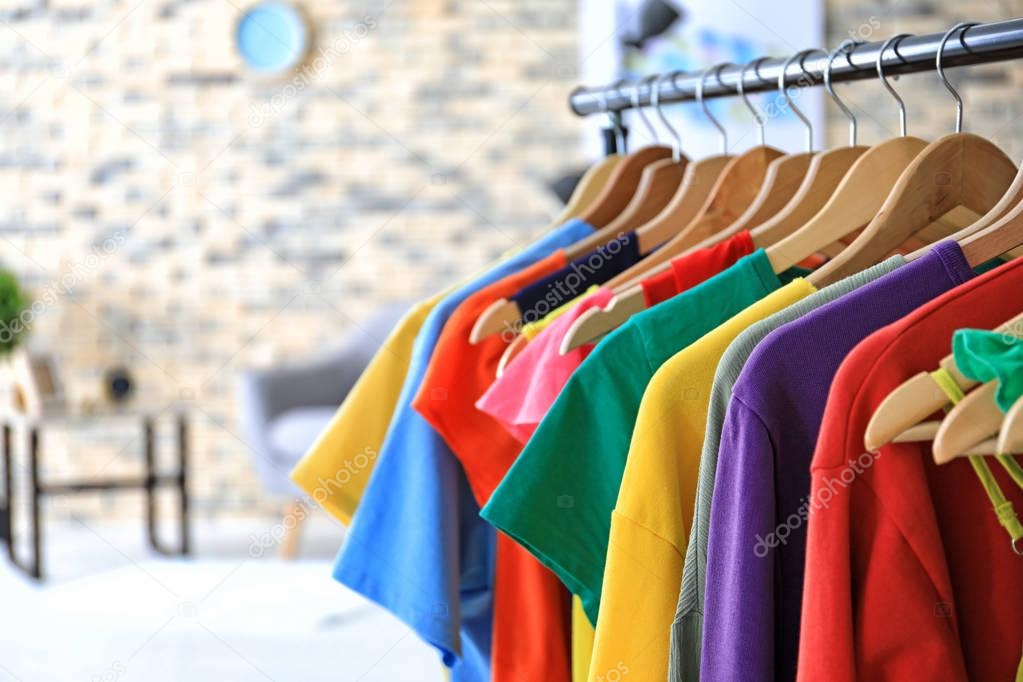 Rack with rainbow clothes on hangers indoors