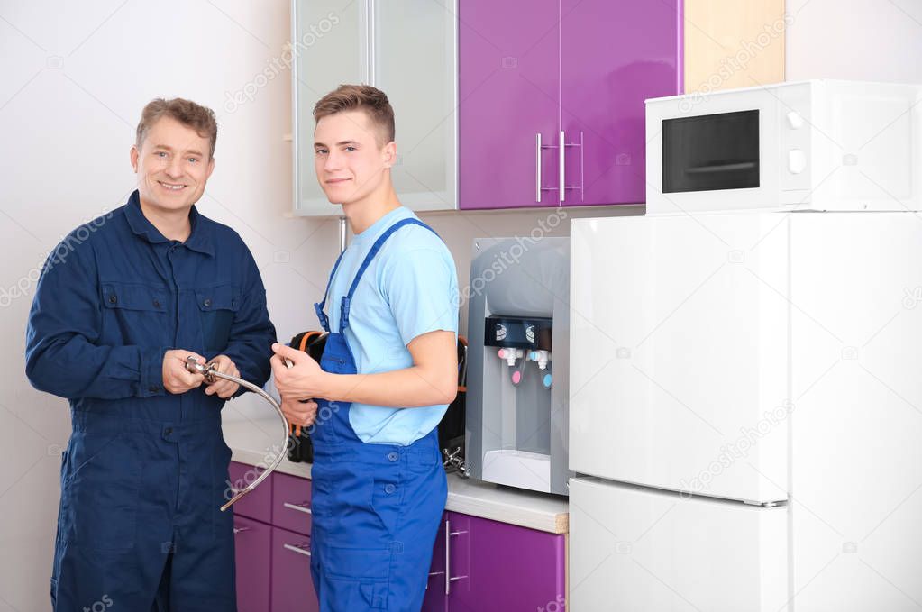 Plumber with young trainee in kitchen