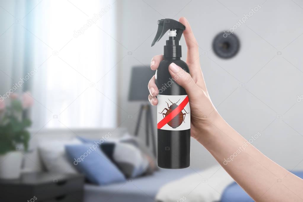 Woman holding bottle of anti bed bug detergent in bedroom