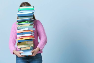 Öğrenci ders kitapları yığını renk arka plan üzerinde taşıyan. Eğitim süreci