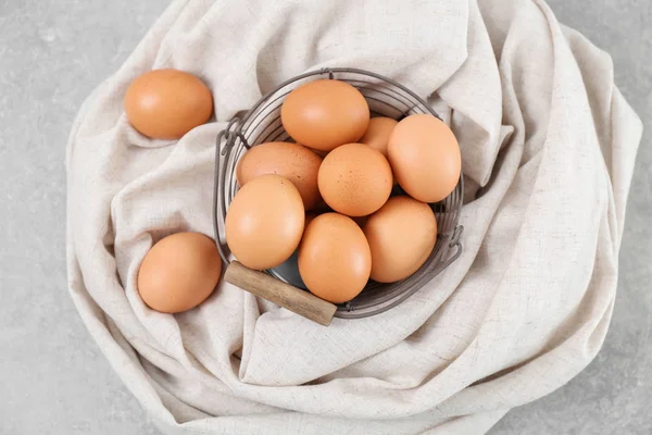 Cesta de metal con huevos de pollo en la mesa — Foto de Stock