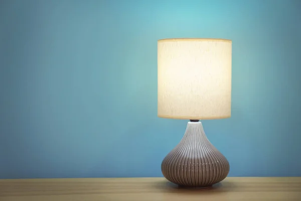 Стильная лампа на столе против цветной стены — стоковое фото