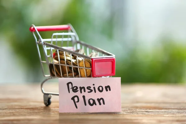 Монети в міні кошику і паперовій картці "PENSION PLAN" на столі — стокове фото