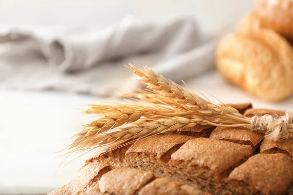 Wheat spikes on freshly baked loaf of bread, closeup — Stock Photo, Image